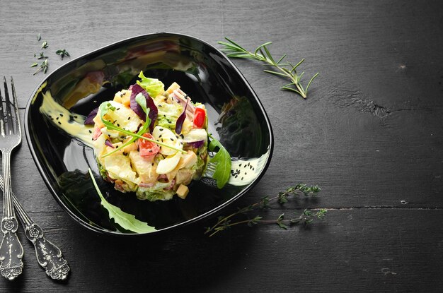 Ensalada de verduras con huevo de pollo y salsa de mayonesa en un plato negro Vista superior Espacio libre para el texto