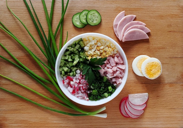 Ensalada con verduras, jamón, huevo y verduras en un plato blanco sobre un fondo de madera