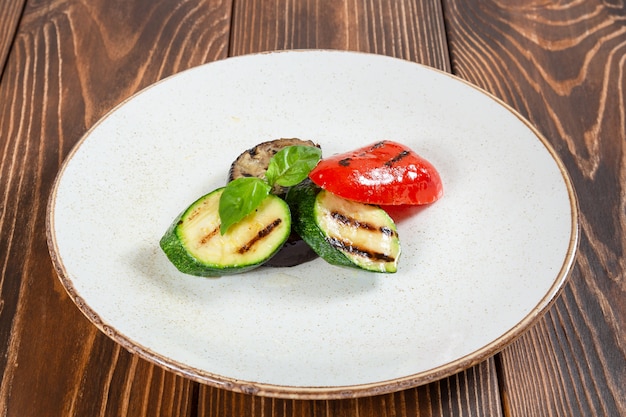 Foto ensalada de verduras a la plancha en la mesa de madera de plato blanco