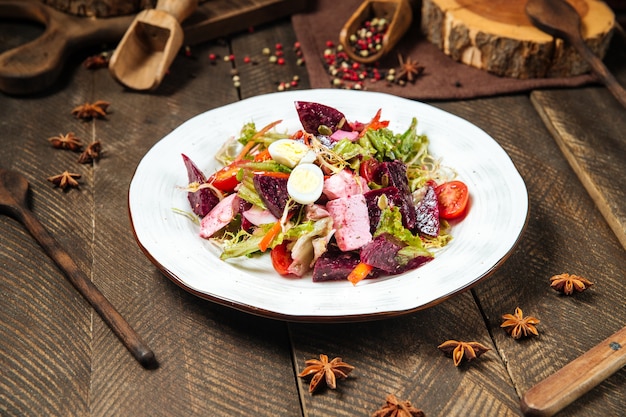 Ensalada de verduras con remolacha, huevos de codorniz y verduras en la mesa de madera decorada