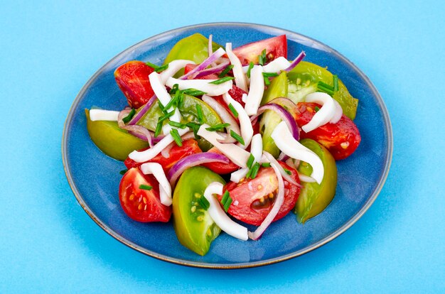 Ensalada de verduras saludable con tomates y trozos de calamar. Foto de estudio.