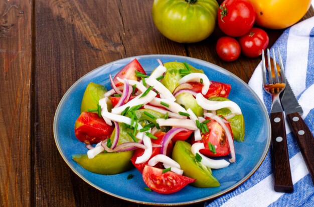 Ensalada de verduras saludable con tomates y trozos de calamar. Foto de estudio.