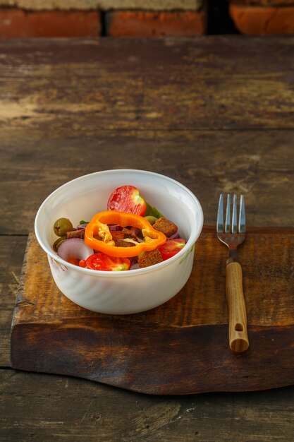 Ensalada de verduras saludables en un plato sobre una mesa de madera junto a un tenedor. Foto vertical