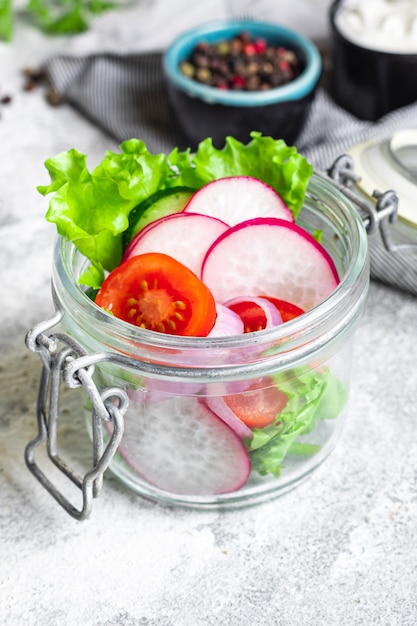 Ensalada de verduras saludables, tomate, pepino, rábano, mezcla de lechuga, porción sobre la mesa