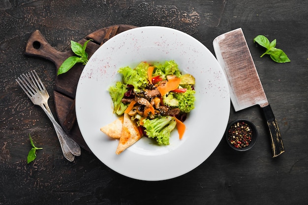 Ensalada de verduras con ternera y champiñones. en el plato Vista superior. Espacio libre para su texto. Estilo rústico.