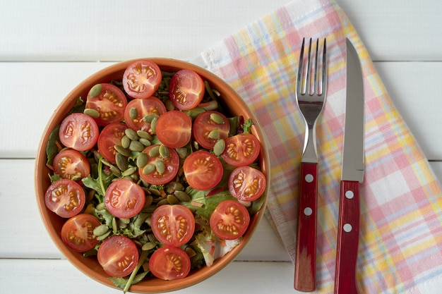 Ensalada de verduras con tomate, lechuga, semillas de calabaza, en una ensaladera.