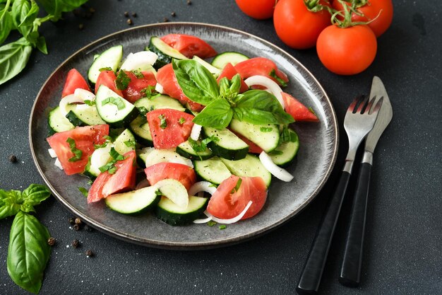 Ensalada de verduras con tomate, pepino y cebolla sobre un fondo de hormigón oscuro