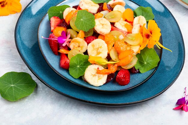 Foto ensalada de vitaminas con plátano, fresas, uvas y capuchina. postres bajos en calorías.