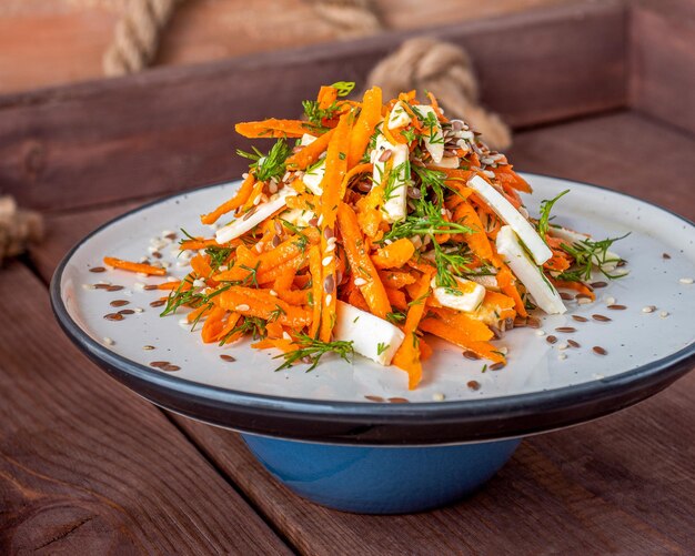 Foto ensalada de vitaminas de zanahorias ralladas con queso y eneldo servida en un plato ligero