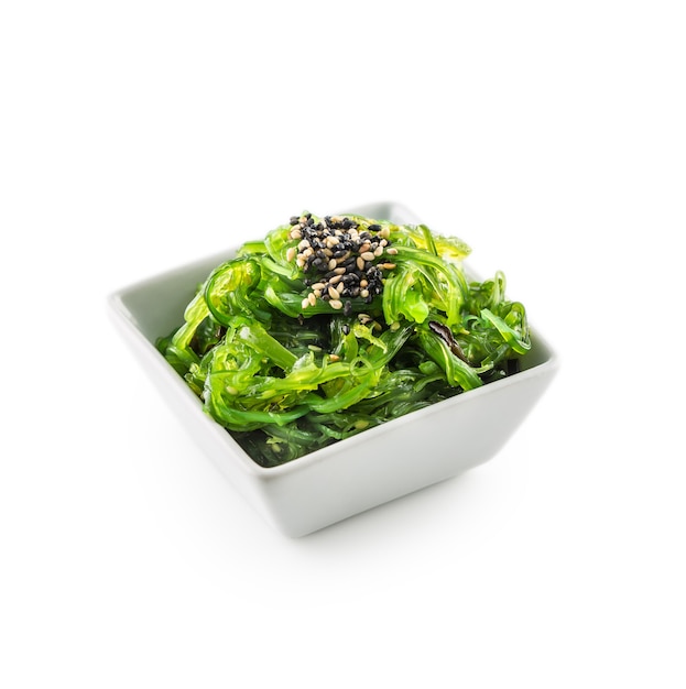 Ensalada de wakame con algas y semillas de sésamo aislado en blanco.