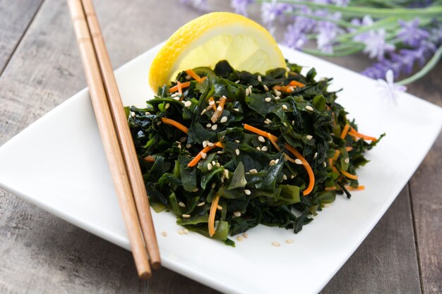 Ensalada de Wakame con zanahoria, semillas de sésamo y jugo de limón en la mesa de madera