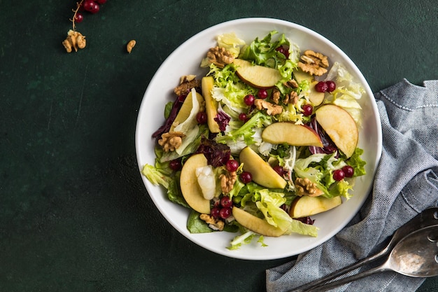 Ensalada Waldorf fresca con lechuga, manzanas verdes, nueces y apio en mesa de madera. Vista superior. Copiar espacio