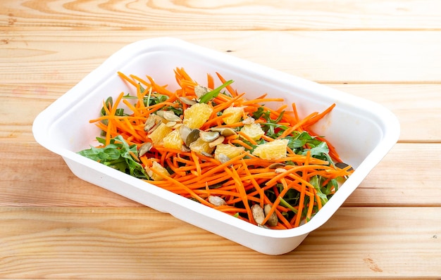 Foto ensalada de zanahorias con naranja comida saludable comida para llevar en un fondo de madera