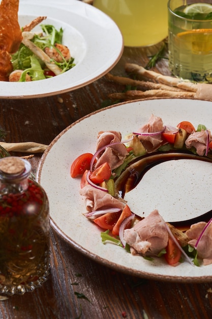Ensaladas con carne de cerdo hervida y camarones en una mesa de madera con salsas