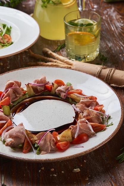 Ensaladas con carne de cerdo hervida en una mesa de madera con salsas