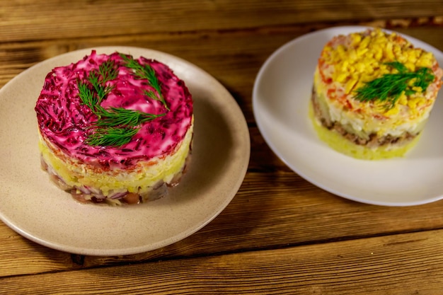 Ensaladas rusas tradicionales en capas Mimosa y Herring bajo un abrigo de piel shuba sobre una mesa de madera