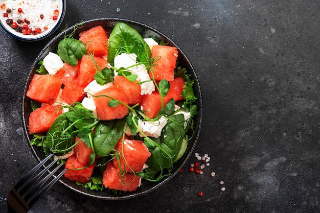 Ensaladera de sandía de verano con espinacas de queso de cabra y brotes de guisantes en el espacio de copia de la vista superior del fondo de la mesa gris