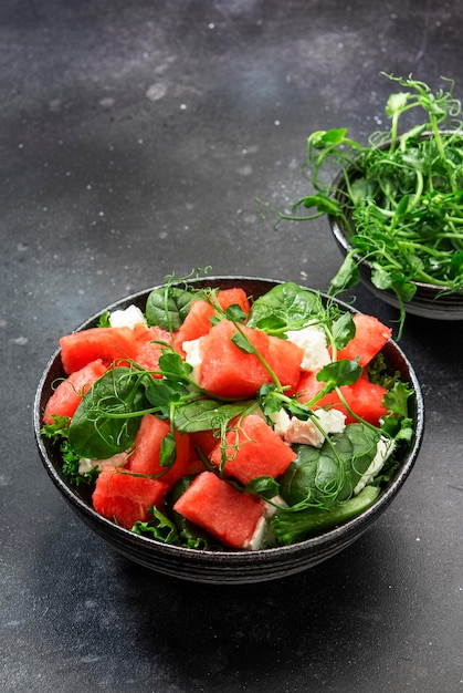 Ensaladera de sandía de verano con espinacas de queso de cabra y brotes de guisantes en el espacio de copia de la vista superior del fondo de la mesa gris