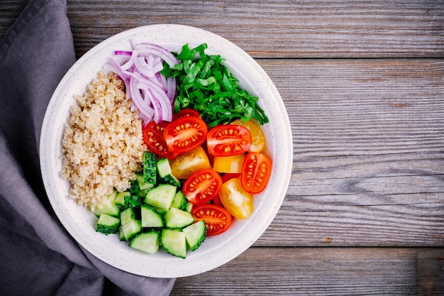 Ensaladera tabulé de quinoa de desintoxicación saludable con pepinos frescos, tomates y cebollas rojas