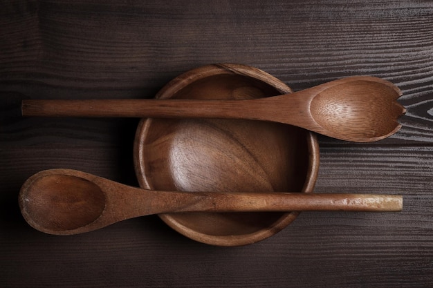 Ensaladera vacía y dos cucharas en la mesa de madera