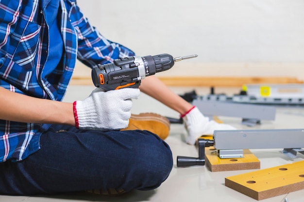 Ensamblar muebles. Hombre sujetando un destornillador eléctrico taladro montaje de muebles, artesano con taladro en destornillador eléctrico