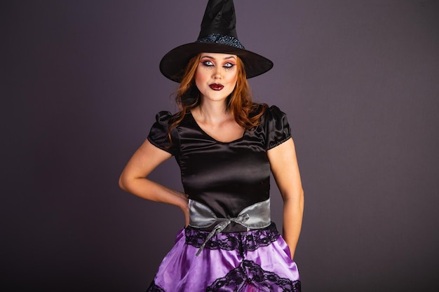 Ensayo de Halloween mujer caucásica vistiendo traje de bruja con las manos en la cintura
