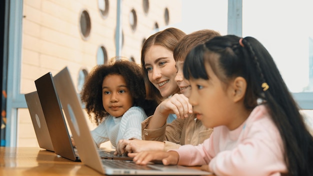 Enseñador inteligente enseñando y estudiante de aspecto usando computadora portátil en el aula erudición