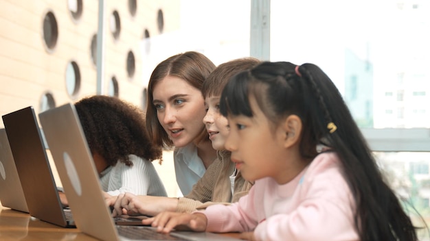 Enseñador inteligente enseñando y estudiante de aspecto usando computadora portátil en el aula erudición