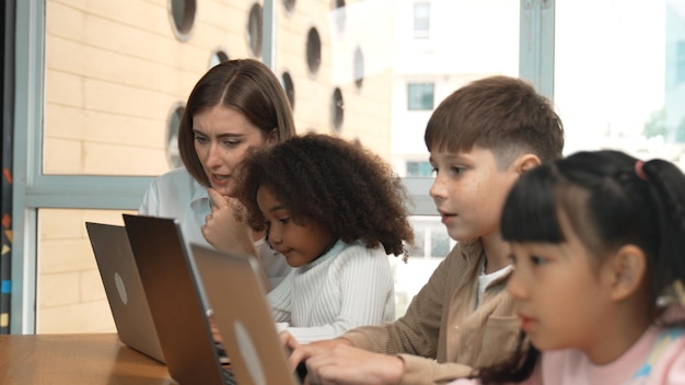 Enseñador inteligente enseñando y estudiante de aspecto usando computadora portátil en el aula erudición