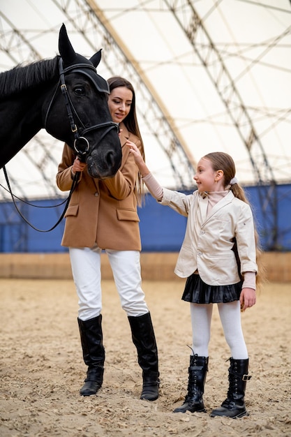 Enseñanza de equitación para niños Niña bonita en traje de jockey y casco