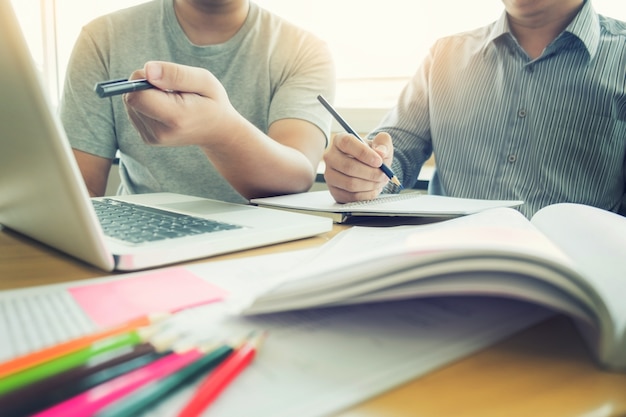 Enseñar el concepto de tecnología de ayuda. mujer joven profesor o tutor con los estudiantes adultos en el aula en el escritorio con papeles, ordenador portátil. estudios curso