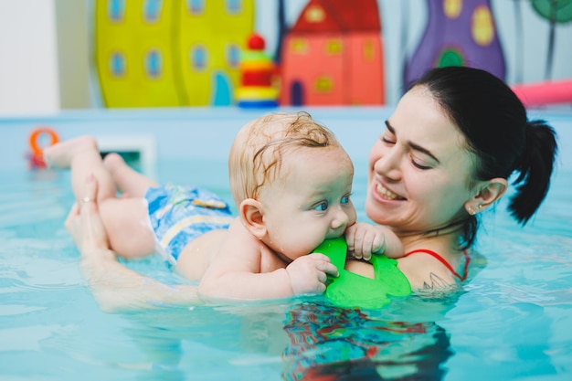 Ensinar as crianças a nadar Um bebê aprende a nadar em uma piscina com um treinador Bebê aprendendo a nadar Desenvolvimento da criança