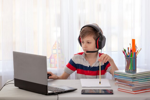 Ensino a distância Criança escrevendo trabalhos de casa com tablet digital. Educação on-line do conceito.