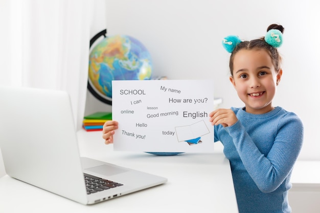 Ensino à distância de inglês para crianças. Ensino doméstico e ensino à distância para crianças. A aluna estuda online com o professor de videochamada.