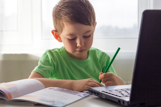 Ensino a distância, educação online. distância social e auto-isolamento durante a quarentena. pré-escolar ou estudante estudando em casa com o notebook e fazendo lição de casa para a escola de desenvolvimento.