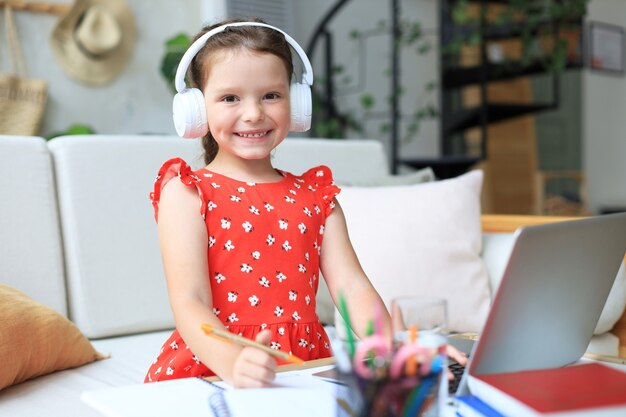 Ensino à distância. menina alegre usando o computador portátil, estudando através do sistema de e-learning online.