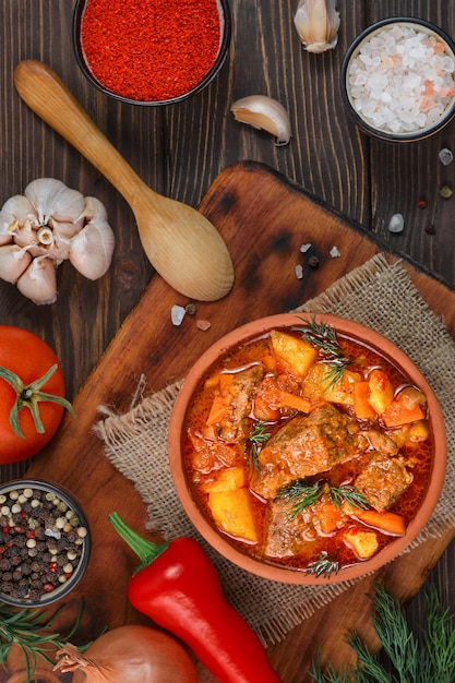 Ensopado de carne com batatas, cenouras, peruca e temperos (goulash húngaro) em uma tigela de barro, vista de cima