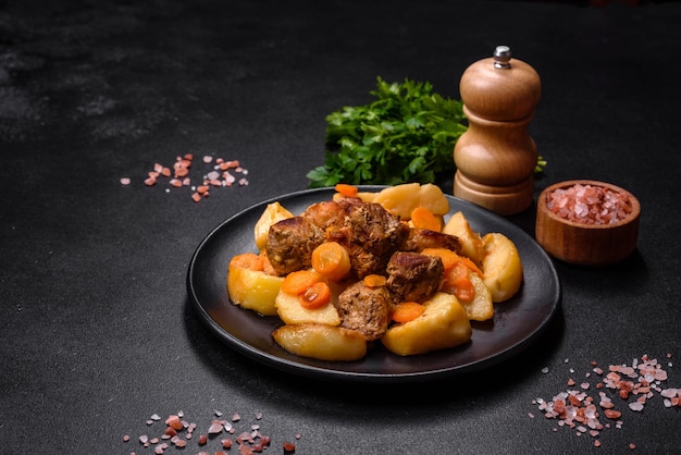 Ensopado de carne e legumes em um prato preto com batatas assadas