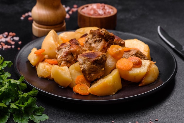 Ensopado de carne e legumes em um prato preto com batatas assadas