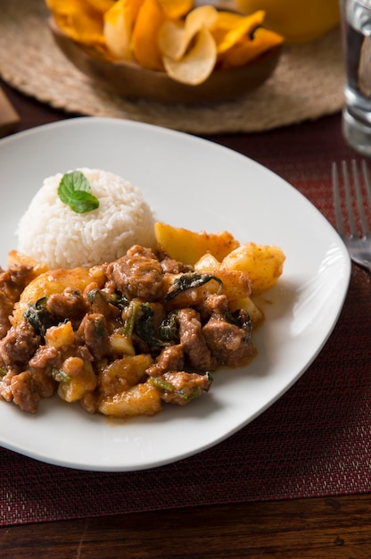 Ensopado de carne fatiada com arroz Peru peruano comida de conforto servindo na mesa de madeira