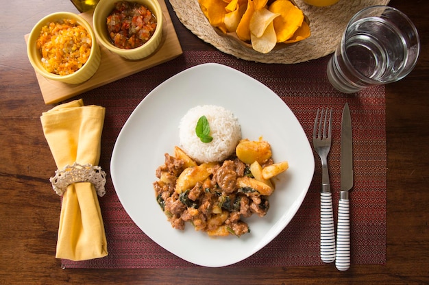 Ensopado de carne fatiada com arroz Peru peruano comida de conforto servindo na mesa de madeira