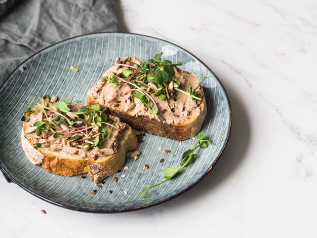 Ente mit zwei Toasts mit Pflaumenrillettenpastete mit Sprösslingen und verschiedenen Samen