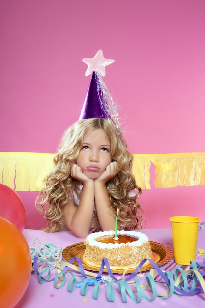 Entediado menina loira pequena festa de aniversário com bolo de vela