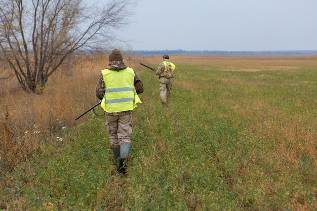 Entenjäger mit Schrotflinte, der durch eine Wiese geht