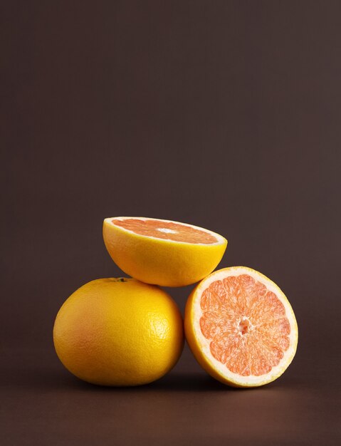 Entero y dos mitades de pomelo sobre un fondo marrón. Fuente de vitamina C.