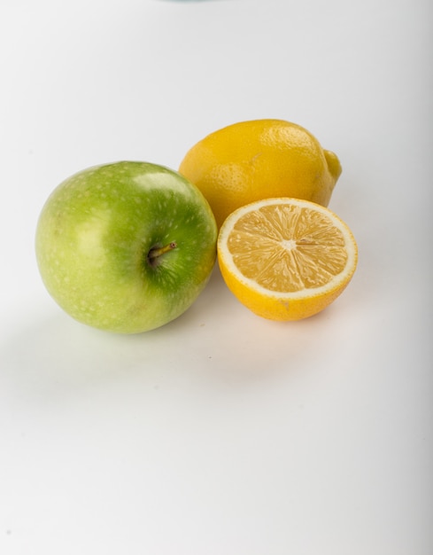 Entero y medio limón aislado en blanco con una manzana verde