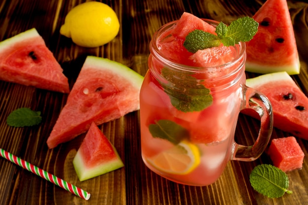 Entgiften Sie Wasser mit Wassermelone und Zitrone auf der braunen Holzoberfläche
