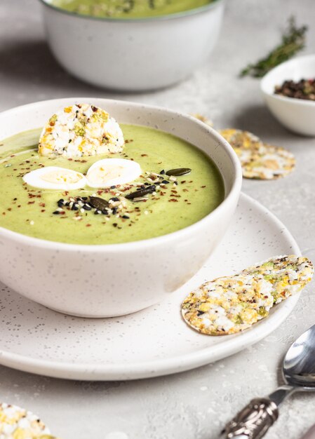 Entgiftungsbrokkolisahnesuppe mit Samenmischung, Wachtelei und Crackern in der Schüssel