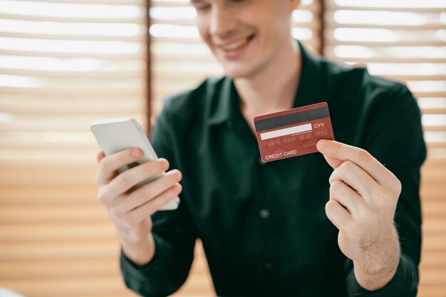 Enthüllung eines jungen Mannes, der einen Laptop mit Kreditkarte für das Internetbanking nutzt