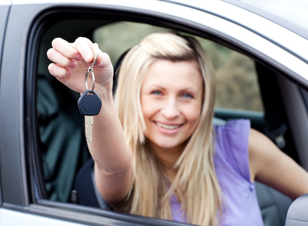 Enthusiastischer junger Fahrer, der einen Schlüssel hält, nachdem er ein neues Auto bying gemacht hat